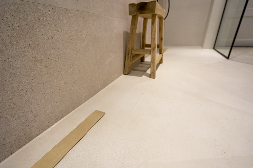 Stuccomeister pro betonstuc badkamer en douchedrain